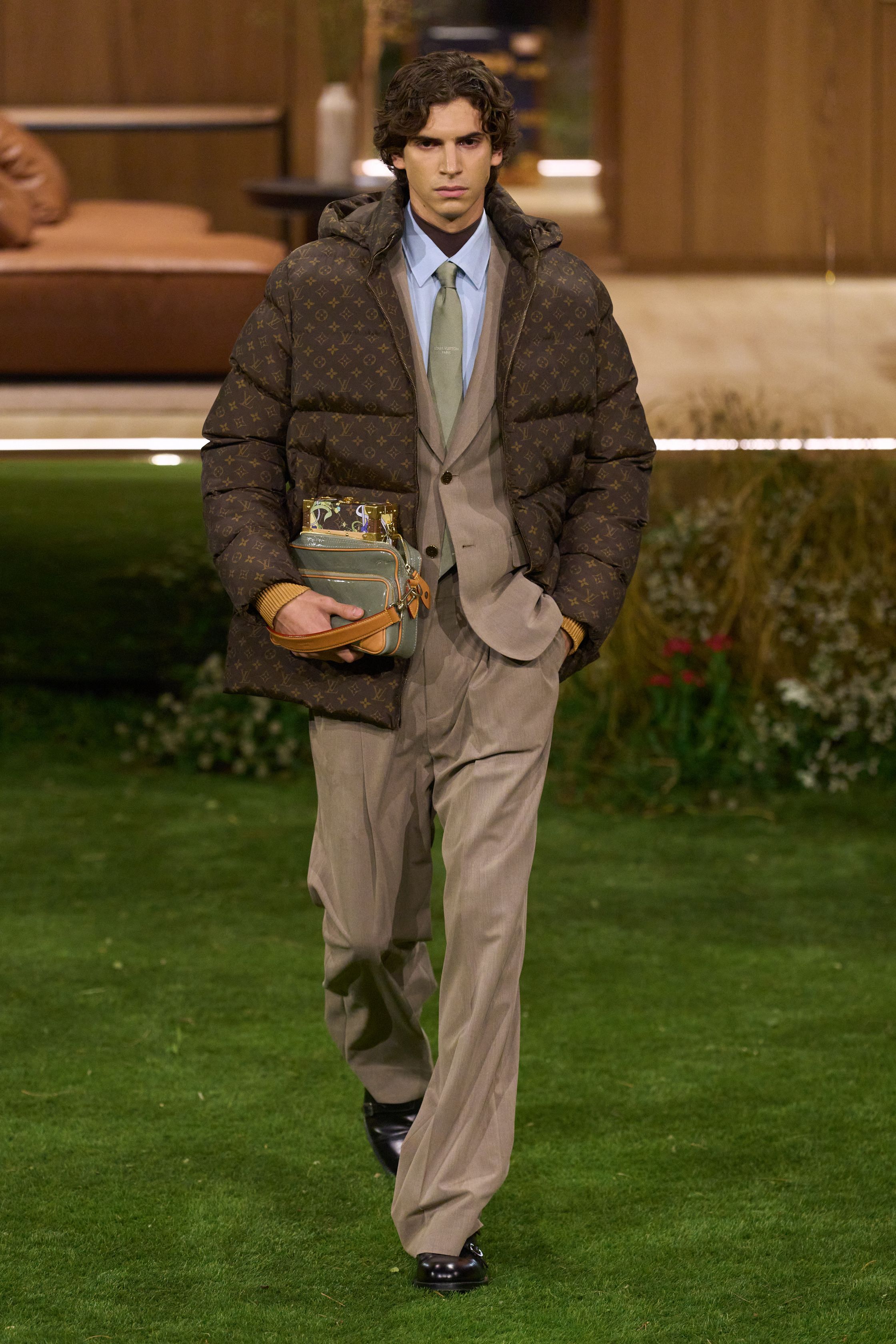 Louis Vuitton 26FW 男装以“当代绅士的旅行状态”为核心，在花园式场景中展开一场关于移动、身份与功能的叙事。功能夹克、细致西装、学院感针织与标志性包袋并行出现，色彩回归卡其、橄榄绿、灰褐与深红，呈现出低调却高度可穿的奢华现实主义。系列强化了“穿着中的生活感”，将品牌传统的旅行基因转译为更克制、更日常的现代衣橱方案-顽石频道趋势研究